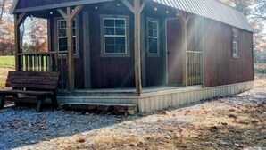 Un rustico chalet in legno con veranda, ampie finestre e tetto in metallo.