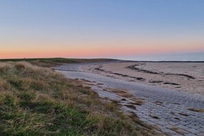Stroll along the coastal pathway to the beach, surrounded by natural dunes.
