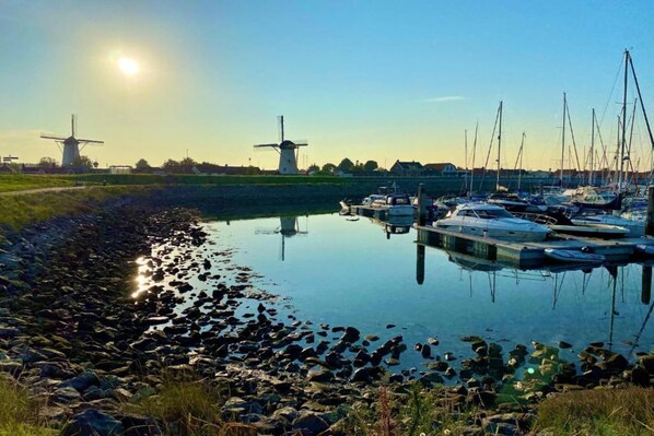 Stunning marina views with boats docked, surrounded by traditional windmills and a rocky shoreline.