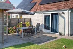 Relax in the patio area with a table and chairs, shaded by a large umbrella.