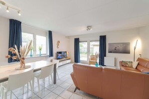 Relax in a spacious living area with a dining table, comfortable sofa, and large windows.