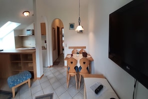 Un espace de vie compact comprenant un coin repas, un téléviseur et une kitchenette.