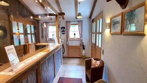 A wooden interior with a reception desk, a bench, and a door leading to a window. - Alpenparadies am Wendelstein (Bayrischzell)
