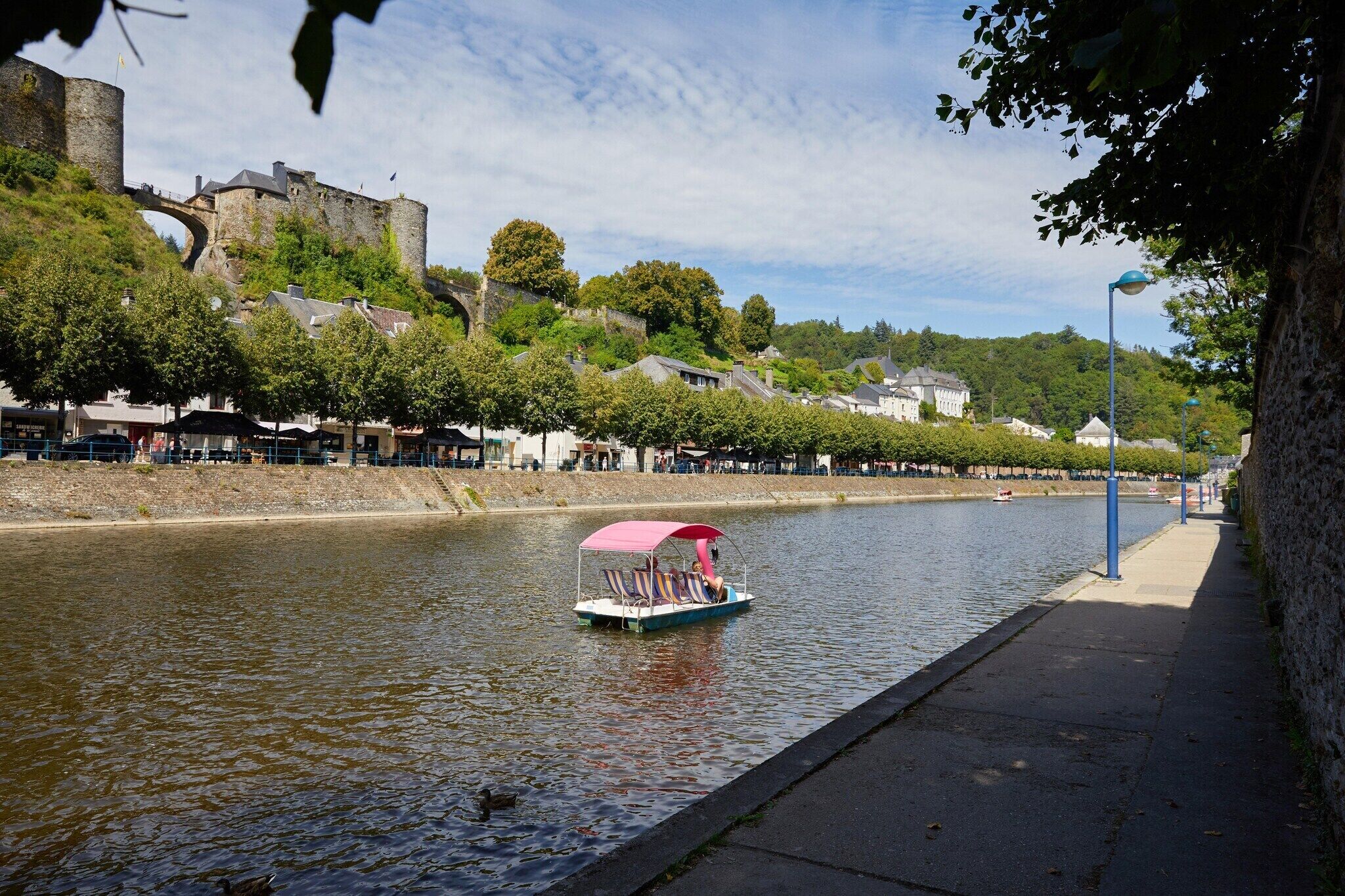 A river with a boat, a castle, and buildings along the riverbank.