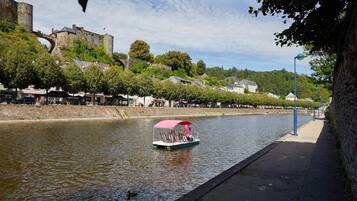 A river with a boat, a castle, and buildings along the riverbank.