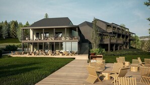 A modern two-story building with a deck area featuring outdoor seating and a staircase leading to an upper level. - Cozy Luxembourg Apartment (Neufchâteau)