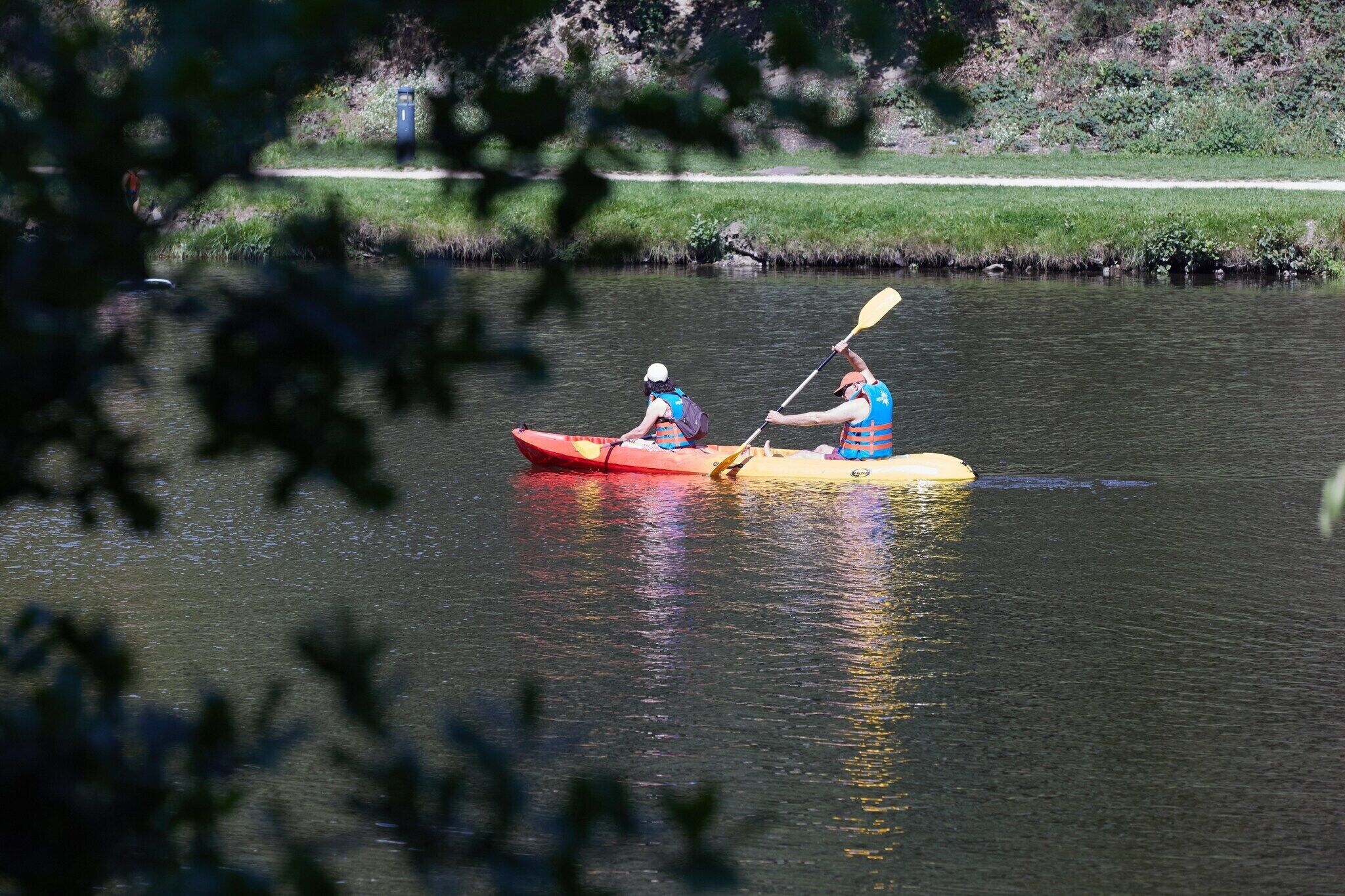 Deux personnes pratiquent le kayak sur une rivière paisible.