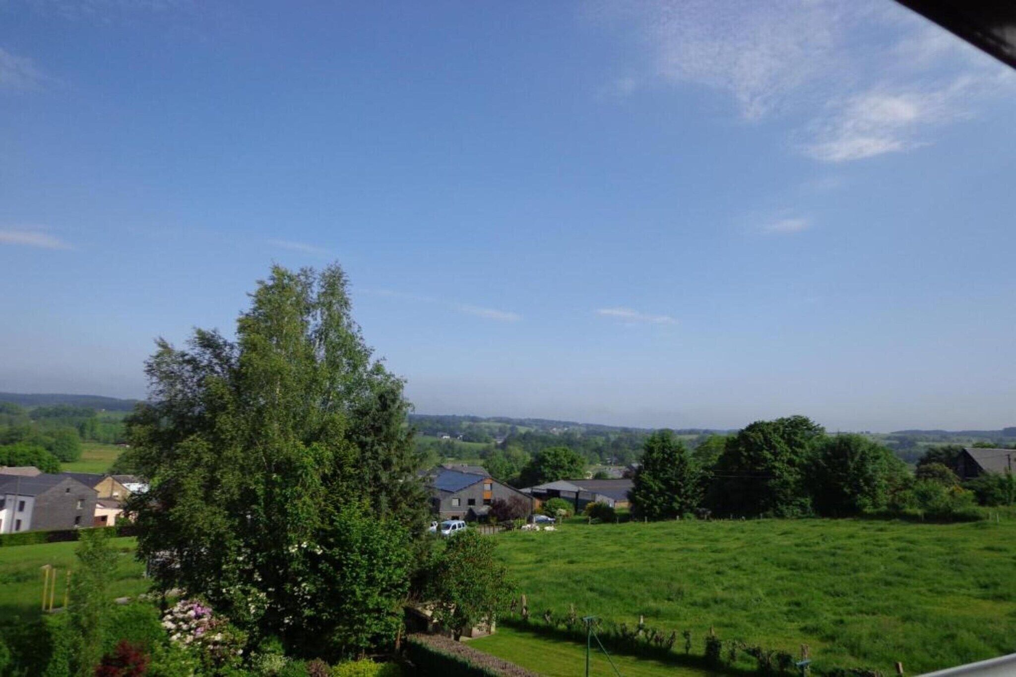 Un paysage rural avec des maisons, un grand arbre et un champ d’herbe.