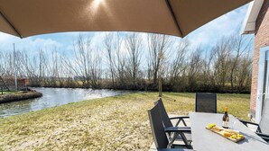 An outdoor patio with a table set for dining, a bottle of wine, and a fruit platter. - Holiday home with lots of privacy (Simonshaven)