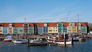 A row of colorful houses by a marina with boats docked in the water. - Holiday home with lots of privacy (Simonshaven)