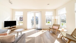 A bright living room with a TV, sofa, chairs, and large windows. - Holiday home with lots of privacy (Simonshaven)