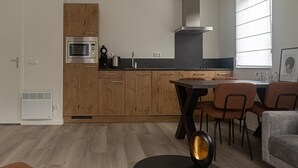 Een moderne keuken met houten kastjes, een ingebouwde magnetron en een eethoek met een tafel en stoelen.