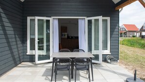 Een donker houten huis met een schuifdeur van glas die leidt naar een keuken.