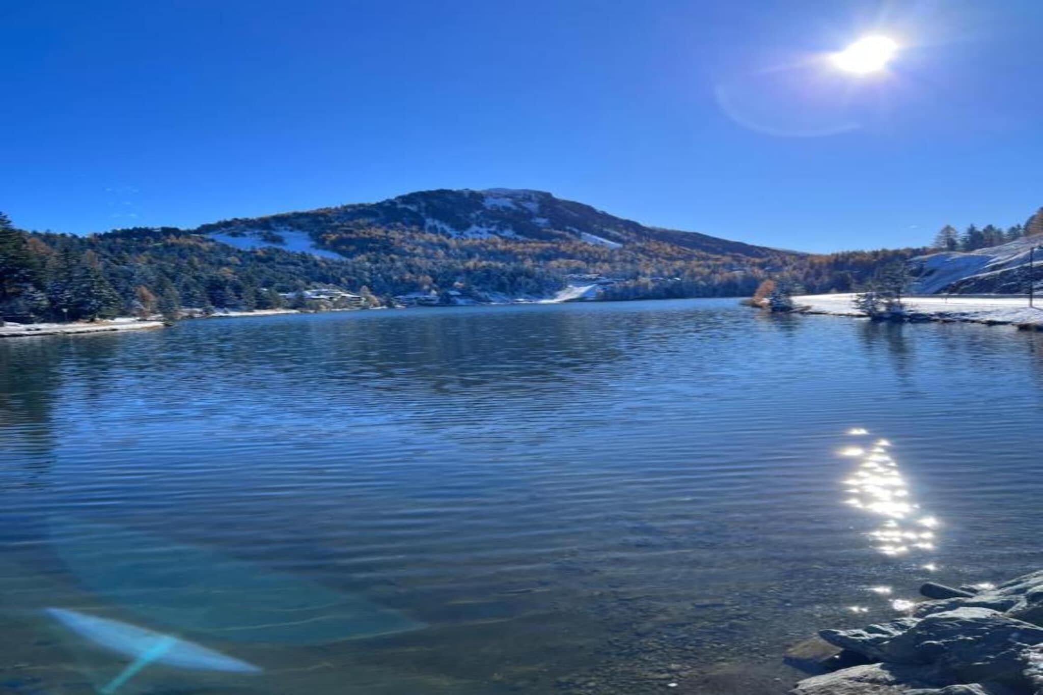 Ein klarer See mit einem Berg im Hintergrund und wolkenlosem Himmel.