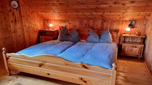 A wooden-paneled bedroom with a bed, two bedside tables, and a wall clock. - Alpine Hut in Murau near Ski Slope (St. Lorenzen ob Murau)