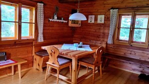 A wooden cabin with a dining table, four chairs, and a hanging light fixture. - Alpine Hut in Murau near Ski Slope (St. Lorenzen ob Murau)