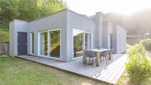 Ein modernes Haus mit Terrasse, großen Schiebegläsern und einem Essbereich.