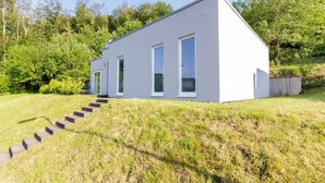 Ein modernes, eingeschossiges Gebäude mit Flachdach, großen Fenstern und einer Betontreppe, die zum Eingang führt.