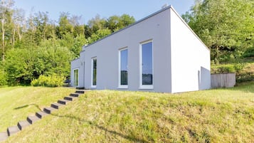 Een modern, gelijkvloers gebouw met een plat dak, grote ramen en een betonnen trap naar de ingang.