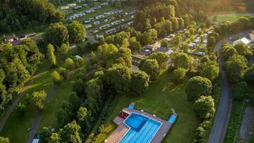 Luchtbeeld van een woongebied met twee zwembaden, omringd door weelderige begroeiing en huizen.