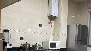 A modern kitchen with a black countertop, a microwave, a refrigerator, and a gas stove.