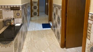 A hallway with patterned tiles, a marble floor, and wooden doors.