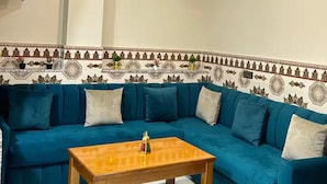 A living room with a teal sofa, a wooden coffee table, and patterned wall tiles. - Fontana apartamento3 (Tanger)