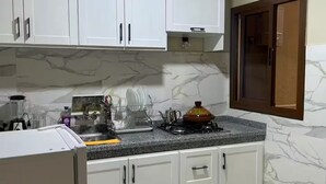 A kitchen with white cabinets, a granite countertop, a stove, and a refrigerator. - Fontana apartamento3 (Tanger)