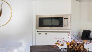 A modern kitchen with a built-in microwave, a coffee machine, and a dining area with a table and chairs.