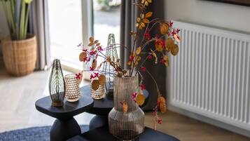 Een kamer met een modern interieur, met een zwart ronde tafel met een glazen vaas met gedroogde bloemen en bladeren, en twee glazen vazen met reliëfdecoratie.