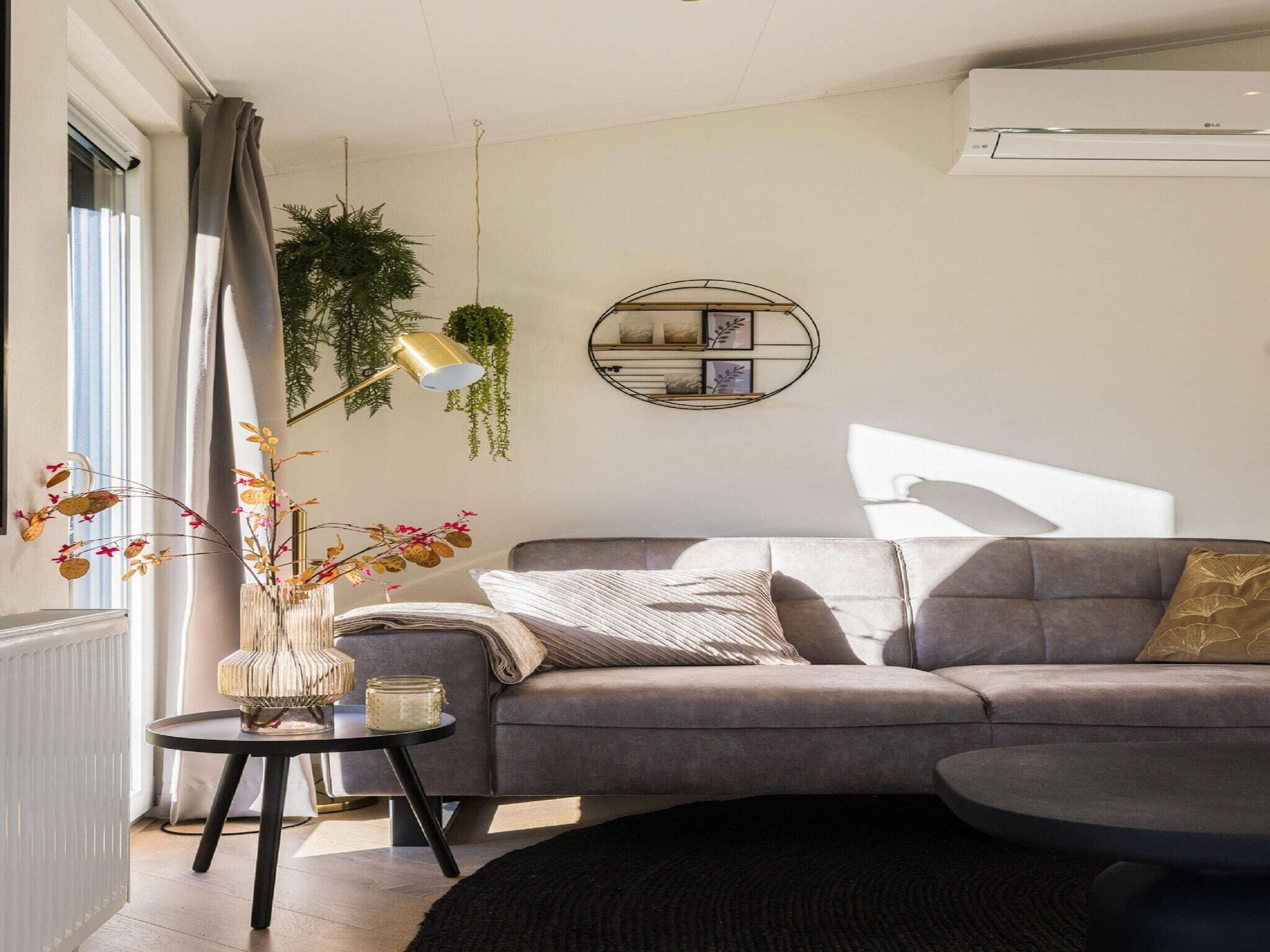 A modern living room with a grey sofa, a round side table, and a black rug.