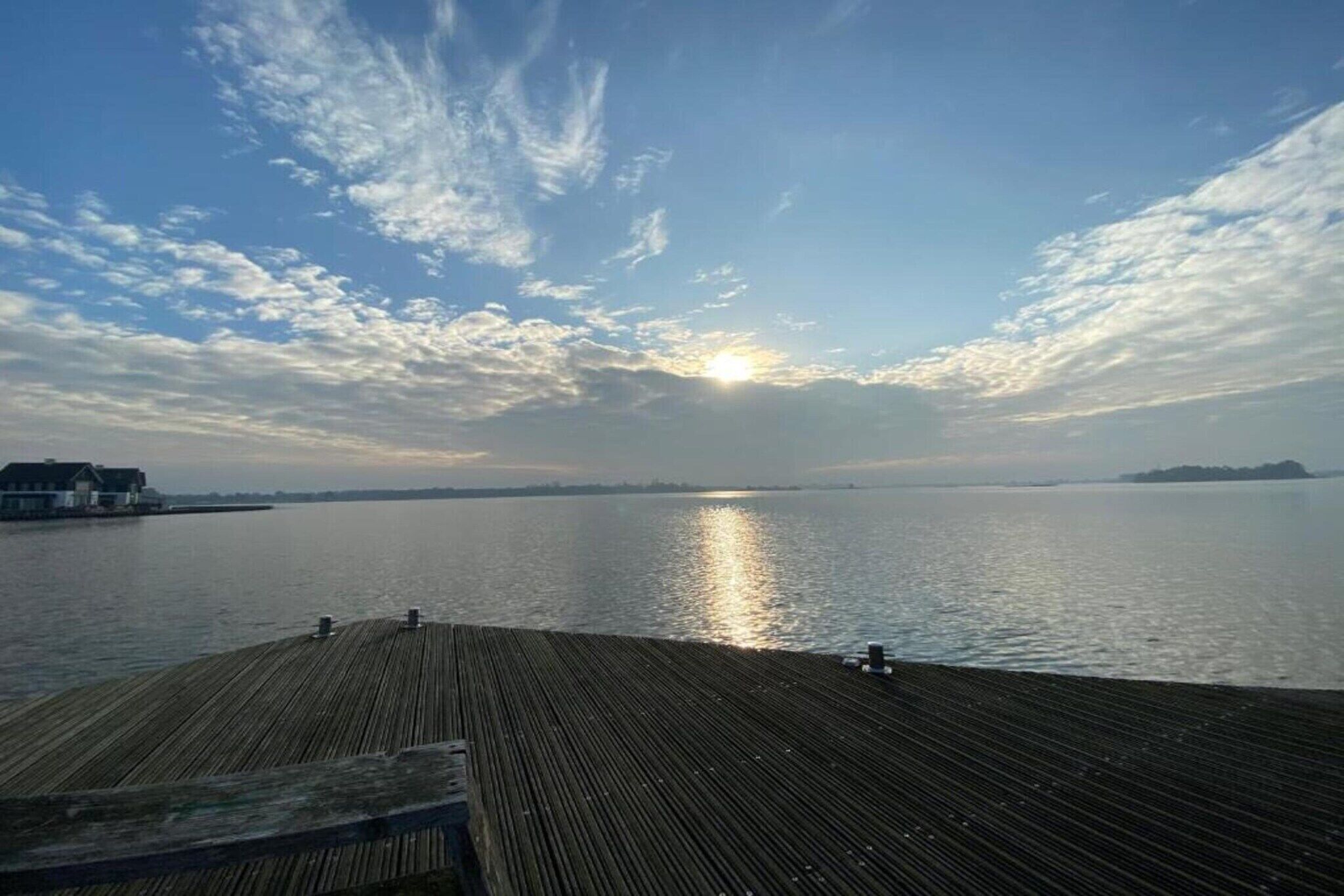 A wooden pier extending into calm water with a sunset in the background.