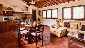 A cozy kitchen with a dining area, featuring a wooden table, chairs, and a sofa. - Farmhouse in Chianti with Pool and Garden (Cavriglia)