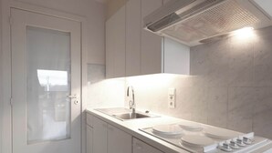 Una cocina moderna con un lavamanos de acero inoxidable, una estufa empotrada y una campana extractora.