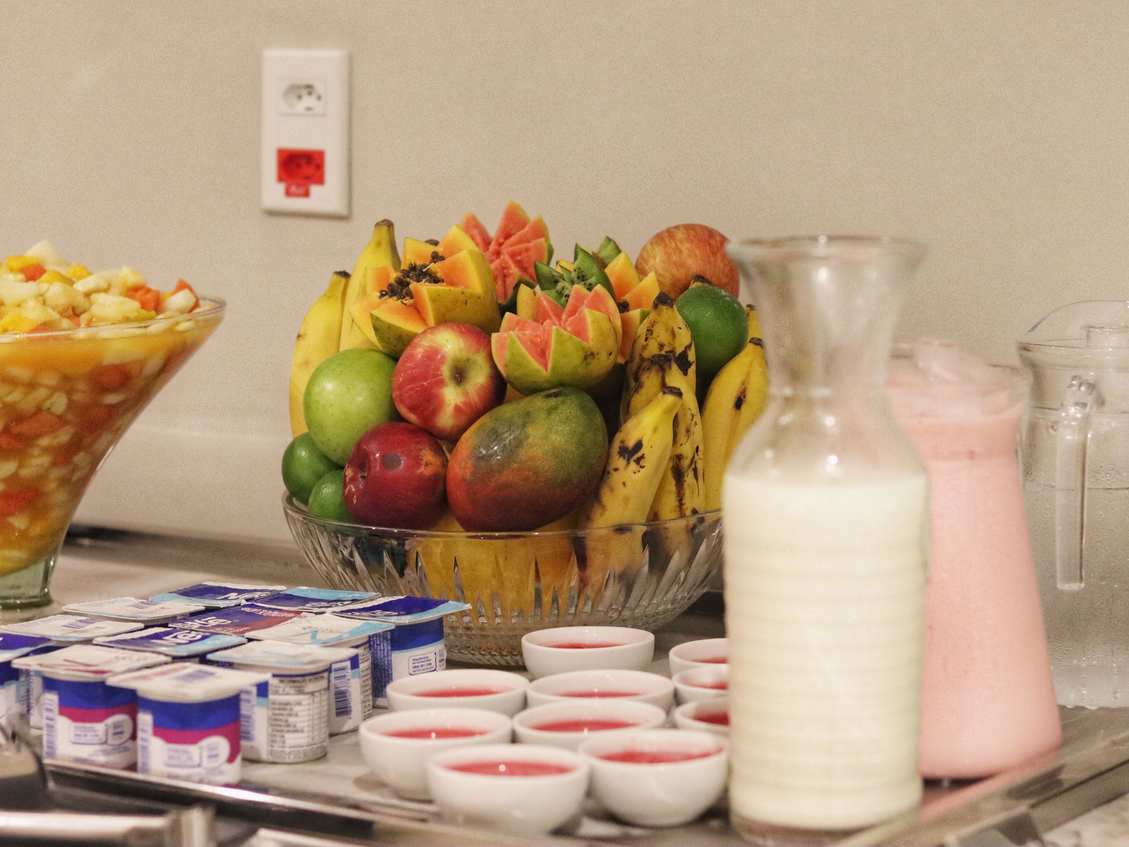 Una mesa de buffet con diversas frutas, yogur y leche.