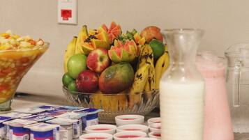 Una mesa de buffet con diversas frutas, yogur y leche.