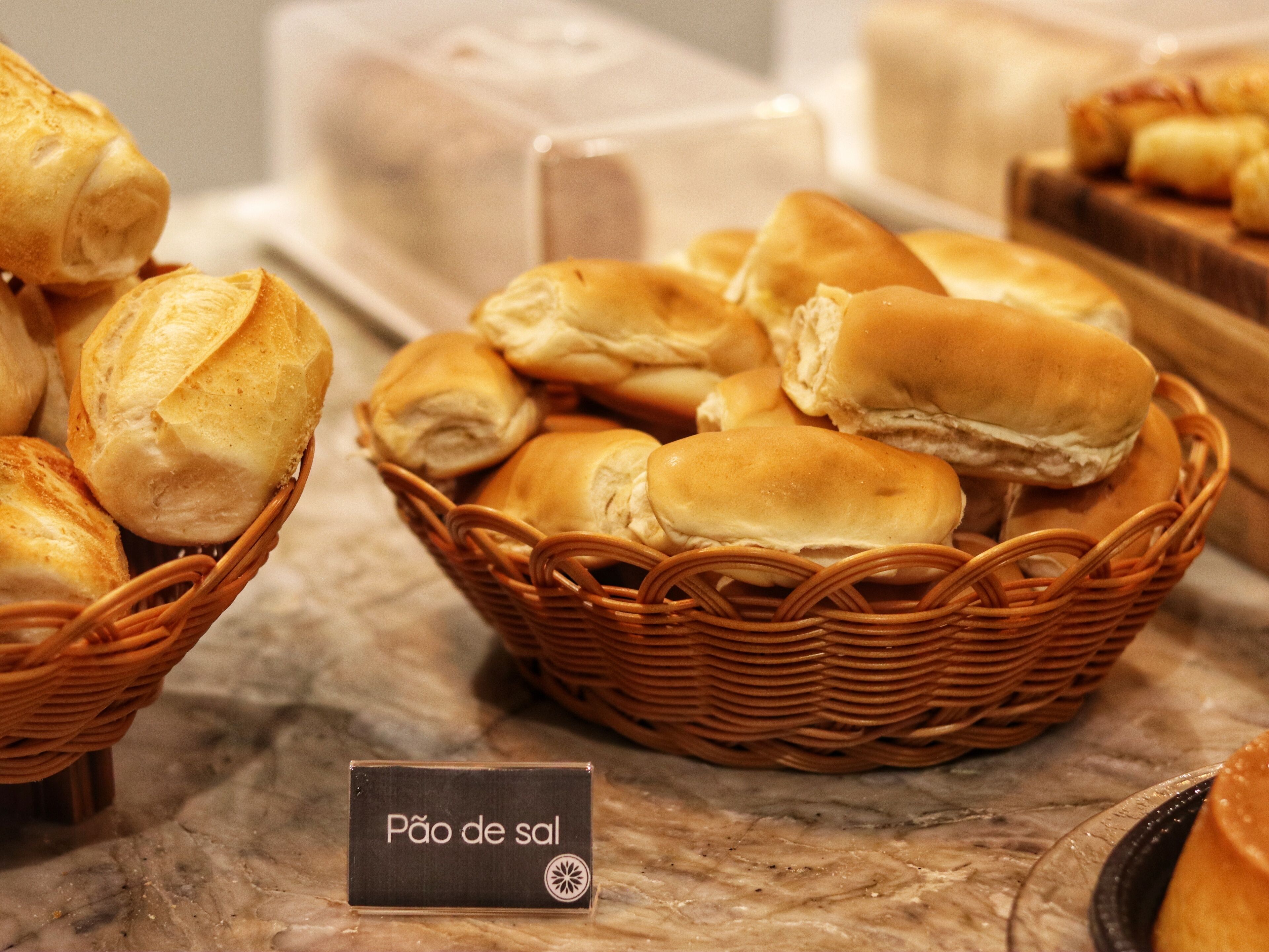 Una cesta de panecillos con un cartel que dice 'Pão de sal'.