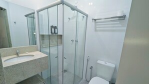 Een moderne badkamer met een douchecabine van glas, een granieten wastafel en een wit toilet.