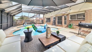 Un patio couvert avec une piscine, du mobilier d’extérieur et un barbecue.