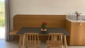 Un coin repas comprenant un banc en bois, deux chaises, une table et une suspension.