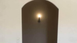 Un couloir étroit doté d’un plancher en bois et d’un luminaire fixé au mur.