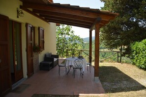 A covered patio with a table and chairs, a wooden pergola, and a view of a mountainous landscape. - Rustic Retreat in Umbria (Monte Santa Maria Tiberina)