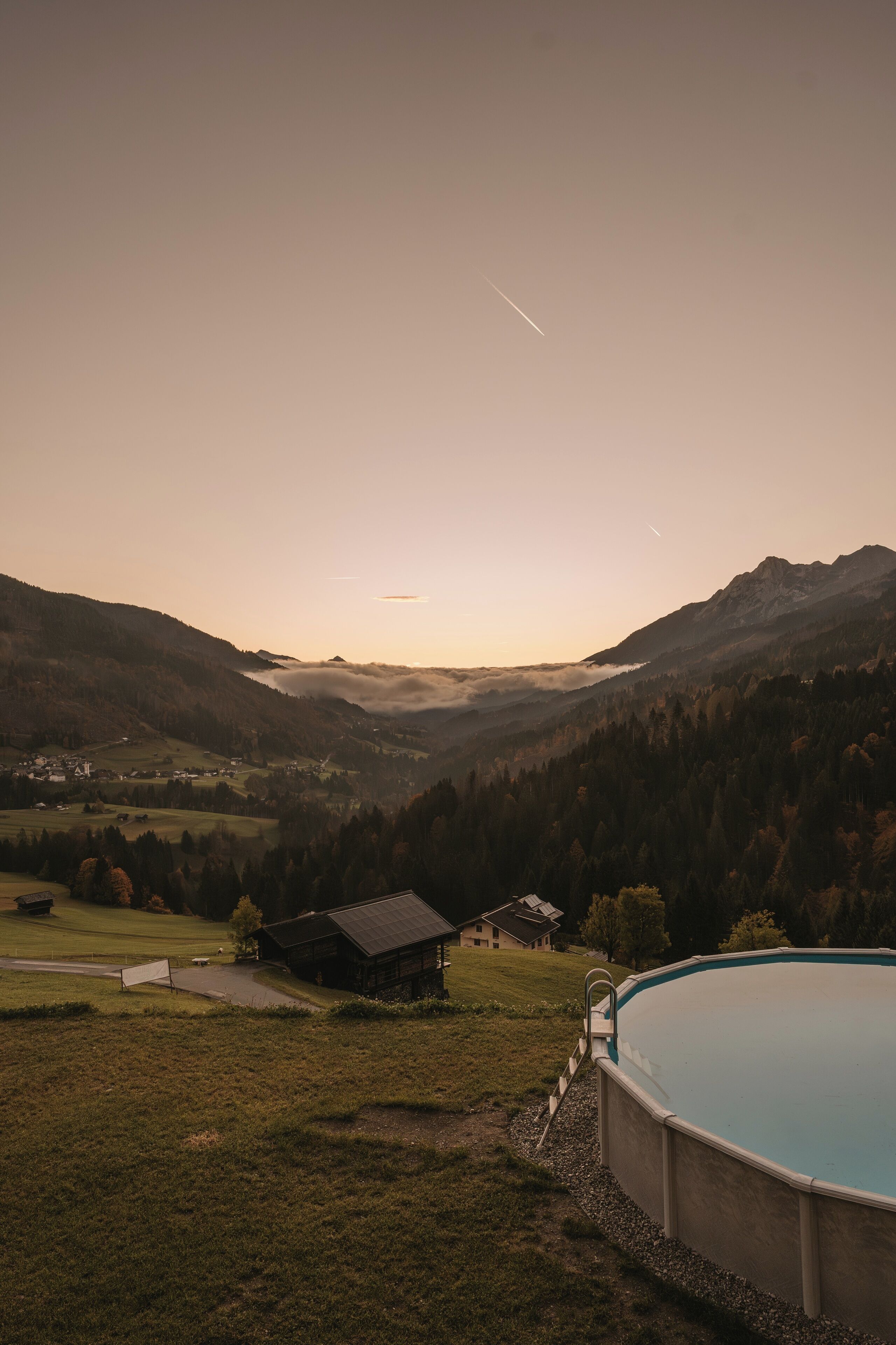 A swimming pool with a view of a mountainous landscape and a small cabin.