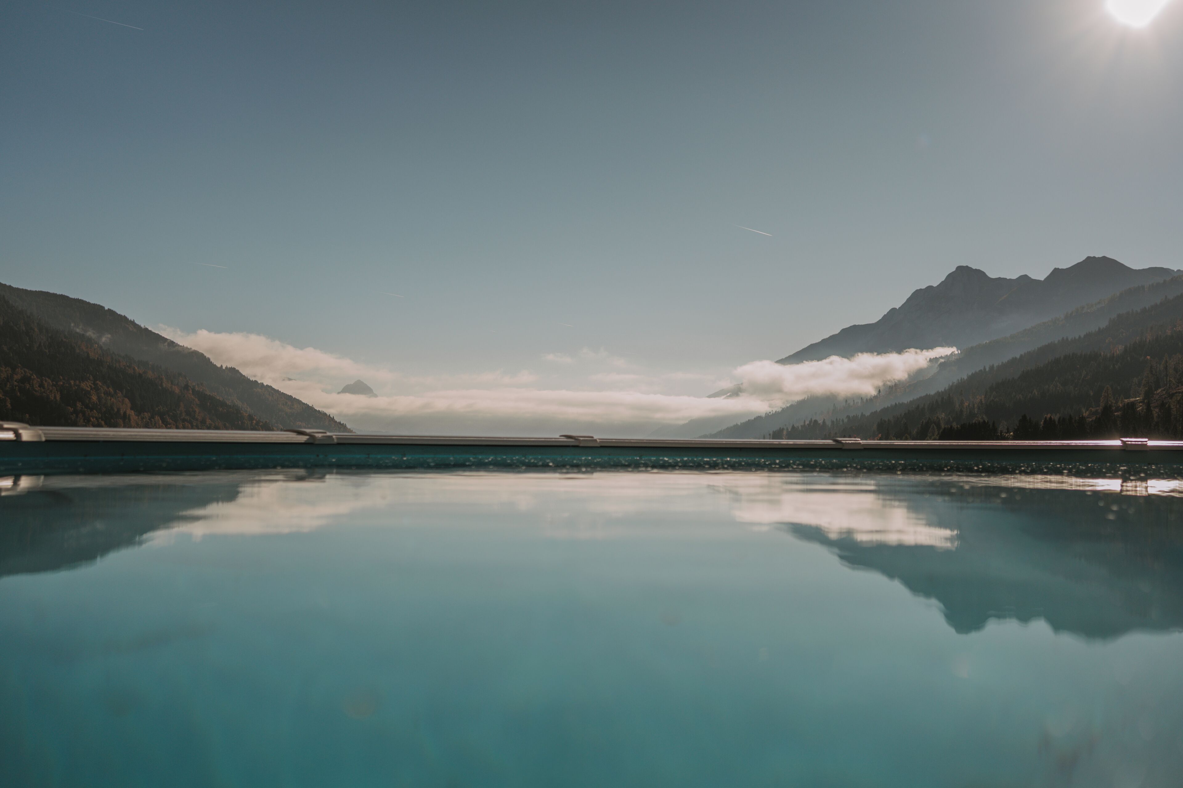 Un lago tranquilo con montañas al fondo y un cielo despejado.