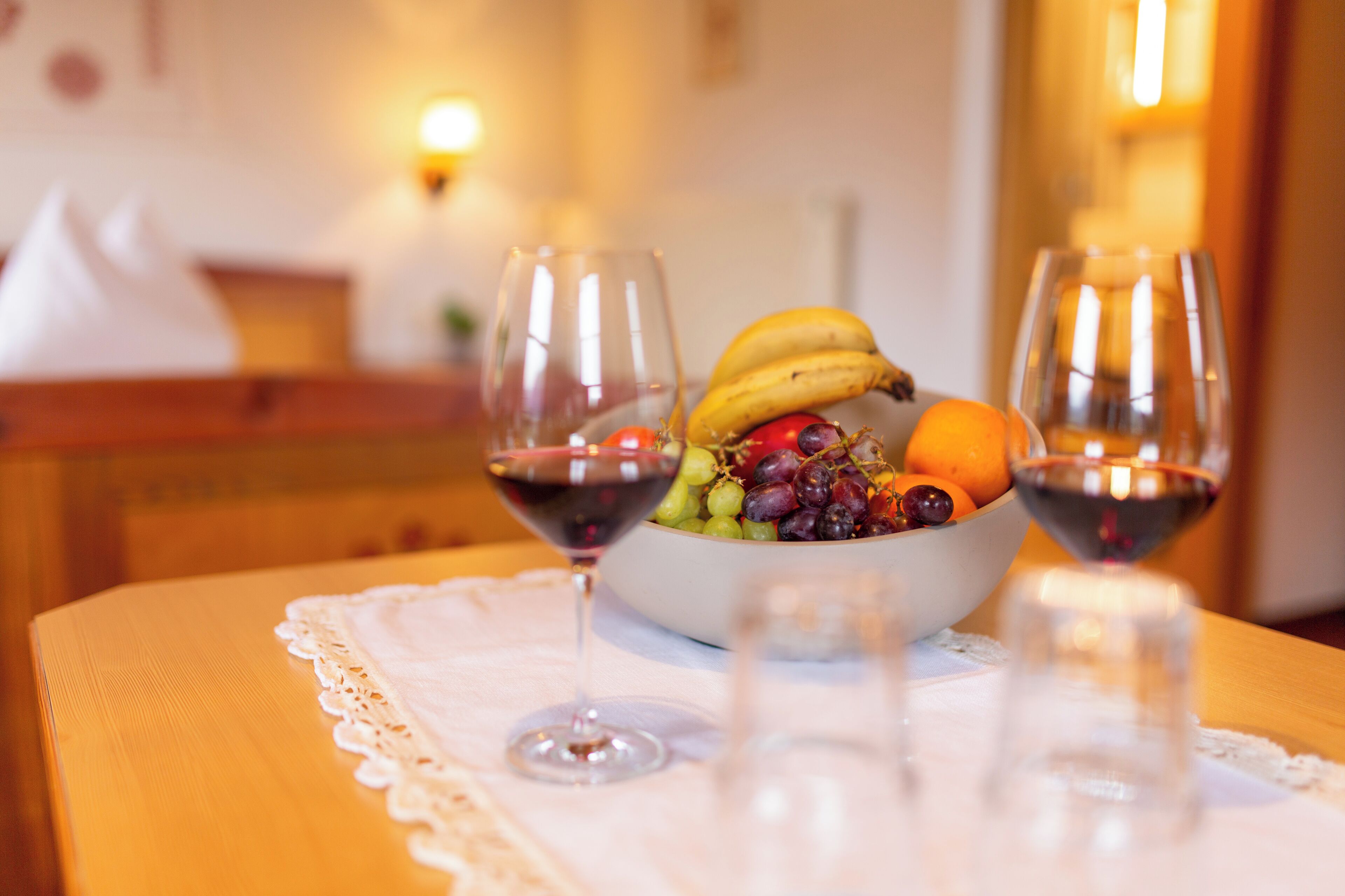 A table with a bowl of fruit and two wine glasses.