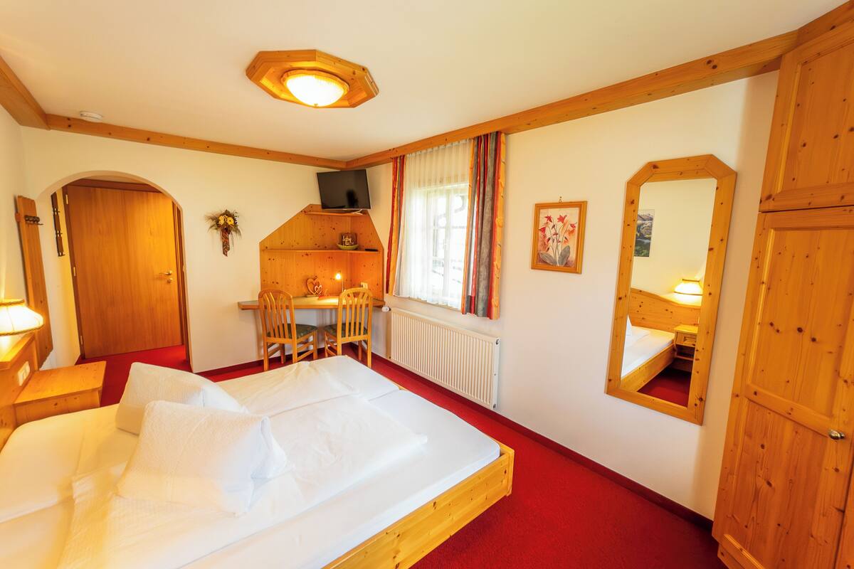 Une chambre à coucher avec un grand lit, un bureau avec deux chaises, une télévision et un miroir.