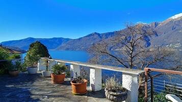 Ein Balkon mit Blumentöpfen und Blick auf Berge und See.