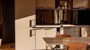 A modern kitchen with stainless steel appliances, a wooden countertop, and a dining area with a table and chairs.