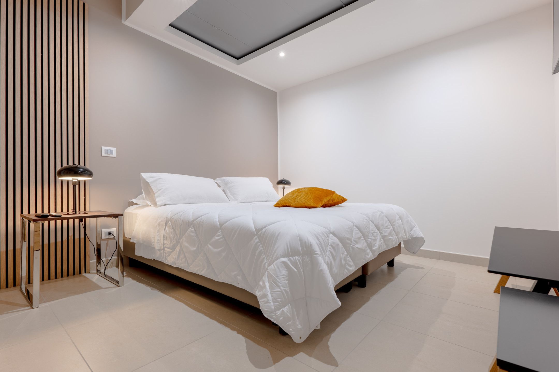 Un dormitorio moderno con cama, escritorio y lámpara.
