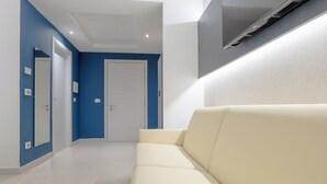En moderne gang med en beige sofa, blå vægge og en hvid dør.